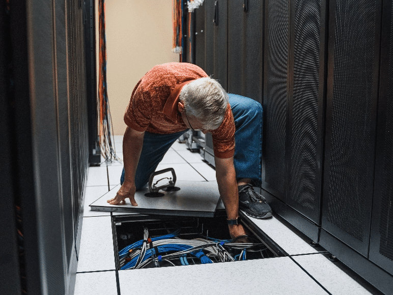 ASD employee adjusting wiring under the floor that keeps reliable infrastructure functioning