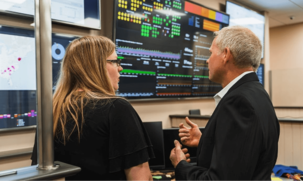 Two Answering Service for Directors team members looking over control screens while having a discussion