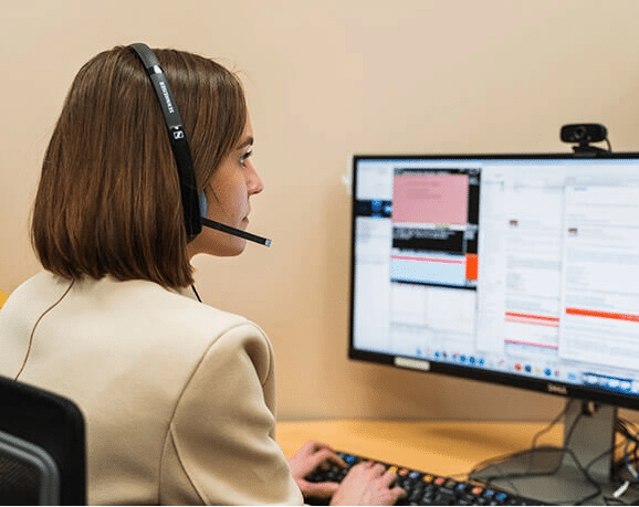 Funeral Call Specialist entering information on the computer while talking on the phone via headset.